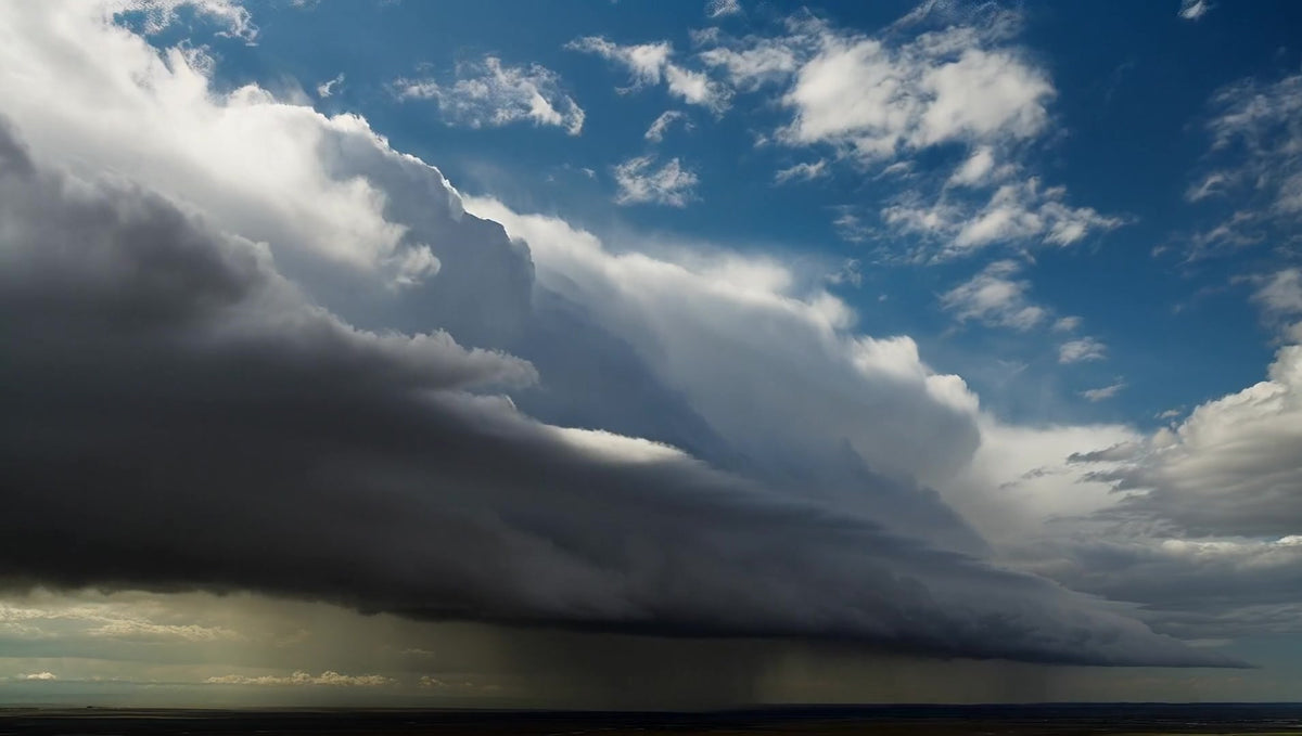 dark storm clouds loom over a landscape of fluffy white clouds against a backdrop of a clear blue sky - Stock Video