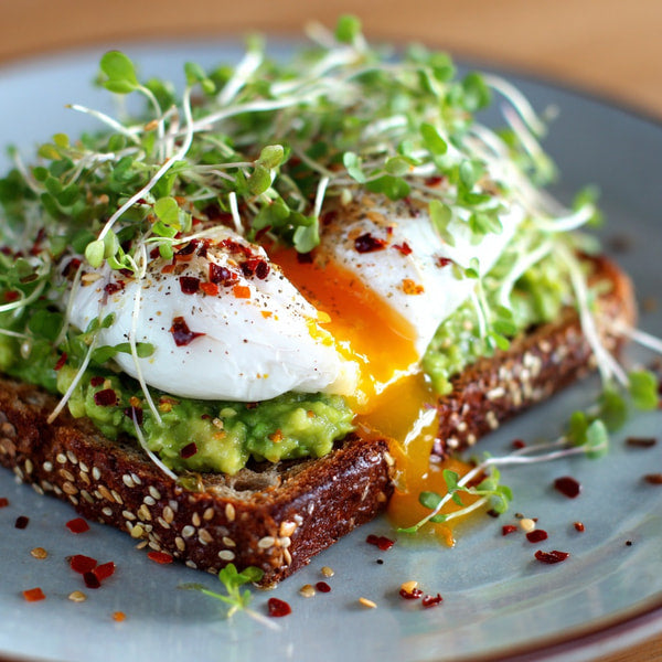 A Plate Of Avocado Toast Topped With A Fried Egg Garnished With Microgreens And Red Pepper Flakes 2 — Stock Photo