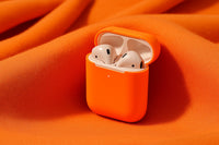 Shows A Small Orange Container With White Earbuds Inside Placed On A Red Fabric Surface — Stock Photo