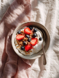 A Bowl Of Yogurt Topped With Berries And Granola Served On A Wooden Table — Stock Photo