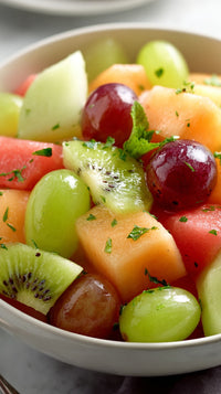 A Bowl Of Fresh Fruit Salad Including Grapes Melon And Kiwi With A Sprig Of Mint On Top — Stock Photo