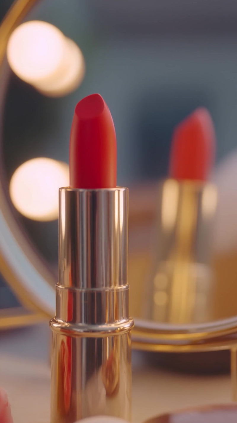 shows a close up of a red lipstick tube with a gold cap placed on a surface with a mirror reflecting it - Stock Video