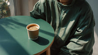 A Person Is Seated At A Table With A Coffee Cup In Front Of Them — Stock Photo