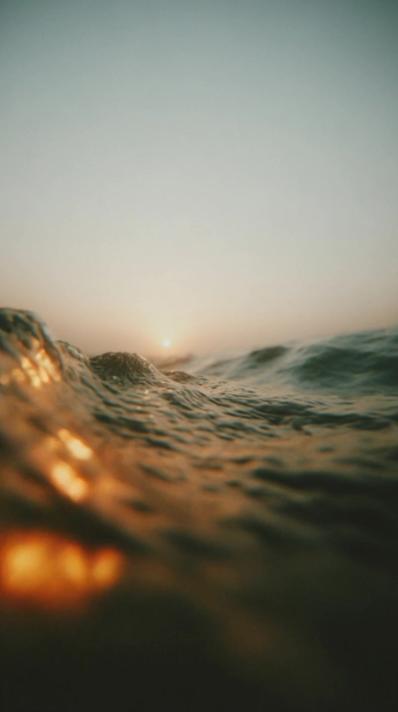 captures a serene sunset scene over the ocean with the horizon line visible in the background - Stock Video