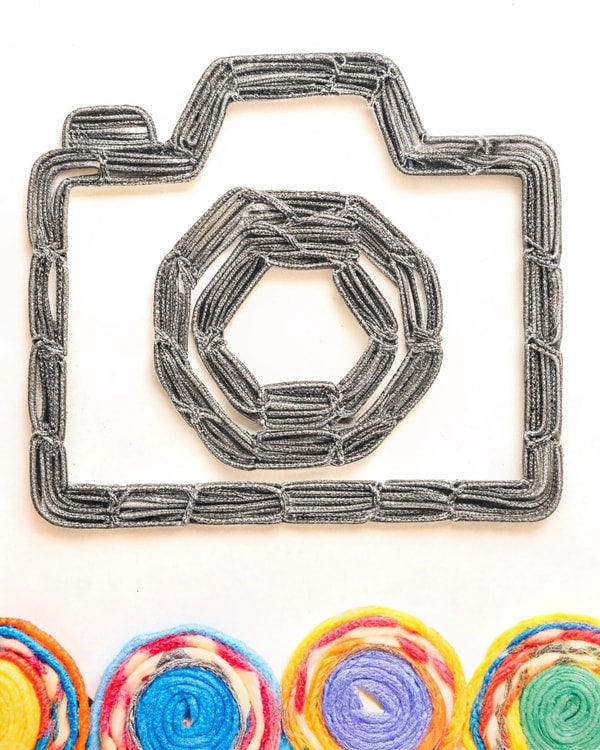 Handmade Camera Decoration With A Hexagonal Design A Central Camera Silhouette Surrounded By A Circular Arrangement Of Colorful Fabric Strips — Stock Illustration