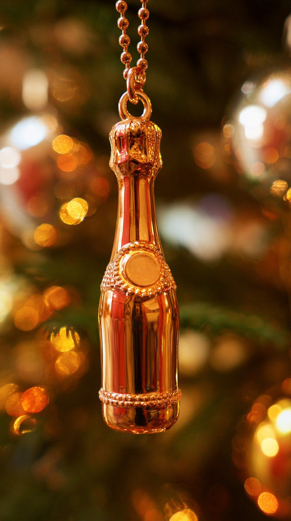 A Copper Colored Bottle Ornament With A Cork Stopper Hanging From A Necklace Against A Festive Christmas Tree Adorned With Gold Baubles — Stock Photo