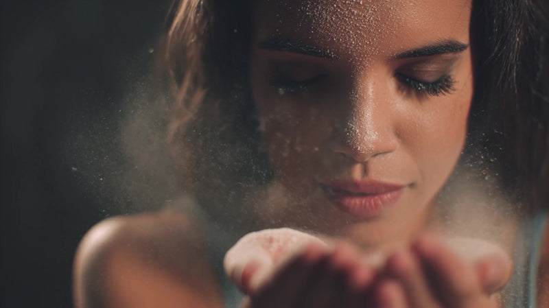 a woman is captured in mid air surrounded by a cloud of flour as she reaches out to grab it with her hands - Stock Video
