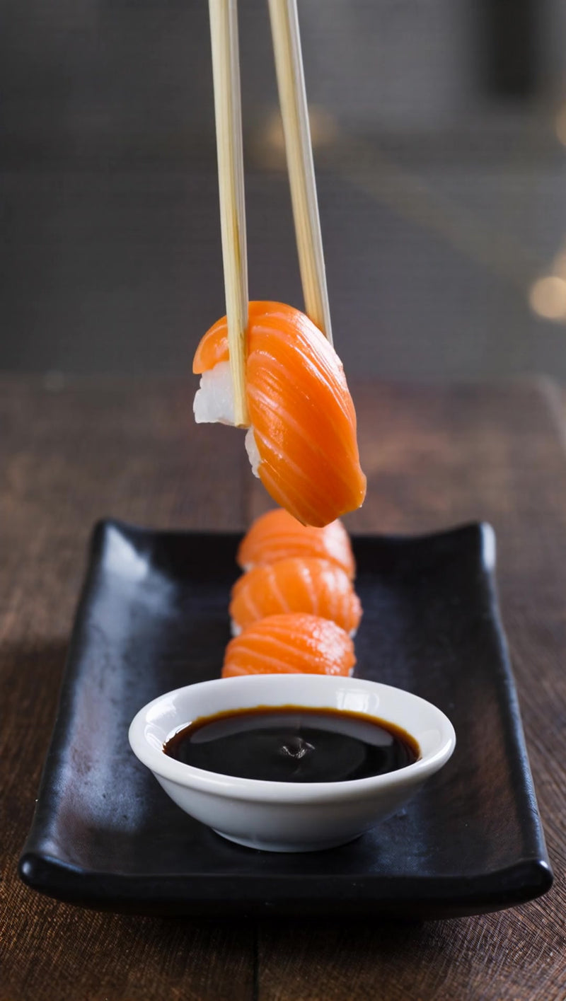 skewered sushi on a black plate served with a small bowl of soy sauce - Stock Video