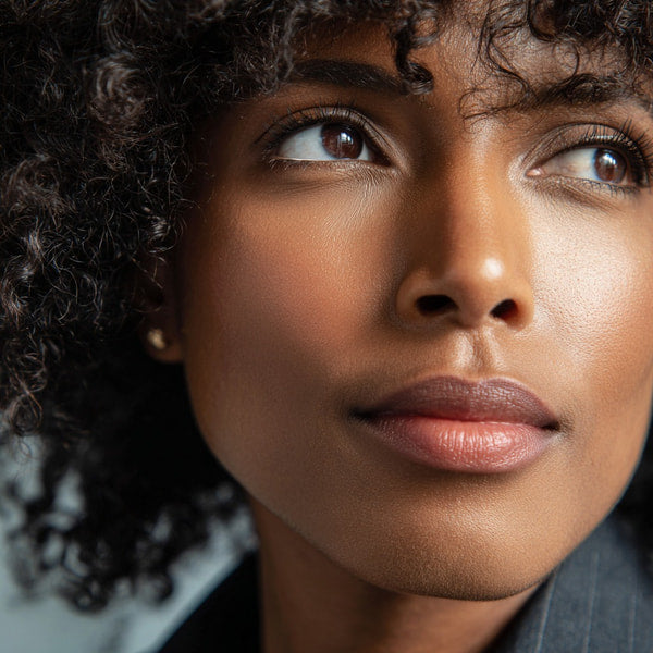 A Woman With Curly Hair Wearing A Black Top And Earrings Looking Directly At The Camera — Stock Photo