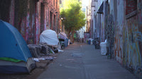 an urban alleyway filled with discarded items and makeshift tents showcasing a sense of neglect and homelessness in an urban setting - Stock Video
