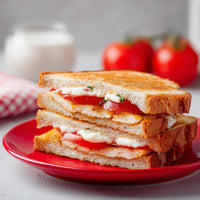 A Grilled Sandwich With Tomato And Cheese Cut In Half And Served On A Red Plate — Stock Photo