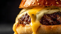 A Close Up Image Of A Cheeseburger With Melted Cheese On Top Served In A Bun And Placed On A Plate — Stock Photo