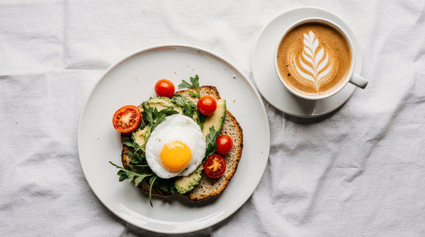 A Plate Of Egg Benedict Served With A Cup Of Coffee And A Leafy Green Garnish Presented On A White Surface — Stock Photo