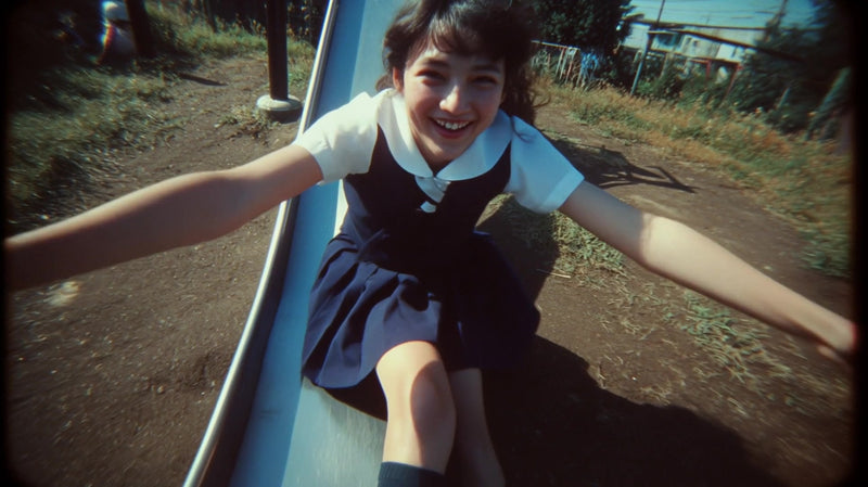 a young girl is captured in mid swing on a playground swing smiling and enjoying her time outdoors - Stock Video