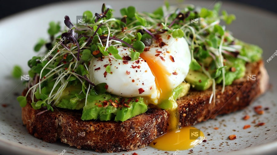 Avocado Toast With Egg Topped With Microgreens And A Sprinkle Of Red Pepper Flakes Served On A White Plate — Stock Photo