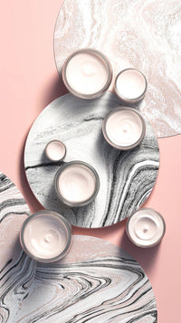 marble candle holders with a marble pattern and three candles placed on them set against a pink background - Stock Video