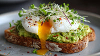 A Plate Of Avocado Toast Topped With A Fried Egg Garnished With Microgreens And Red Pepper Flakes — Stock Photo