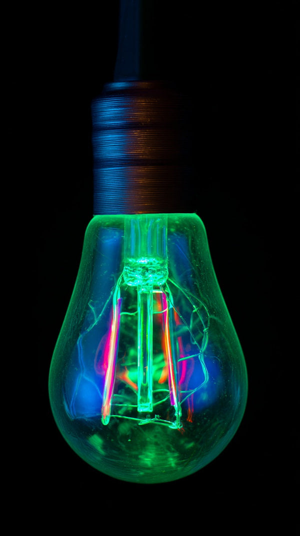 A Neon Light Bulb With A Green Hue And Red Accents Illuminated From Within Set Against A Dark Background — Stock Photo