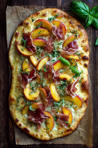 A Pizza Topped With Sliced Peaches Prosciutto And Basil Leaves On A Wooden Cutting Board — Stock Photo
