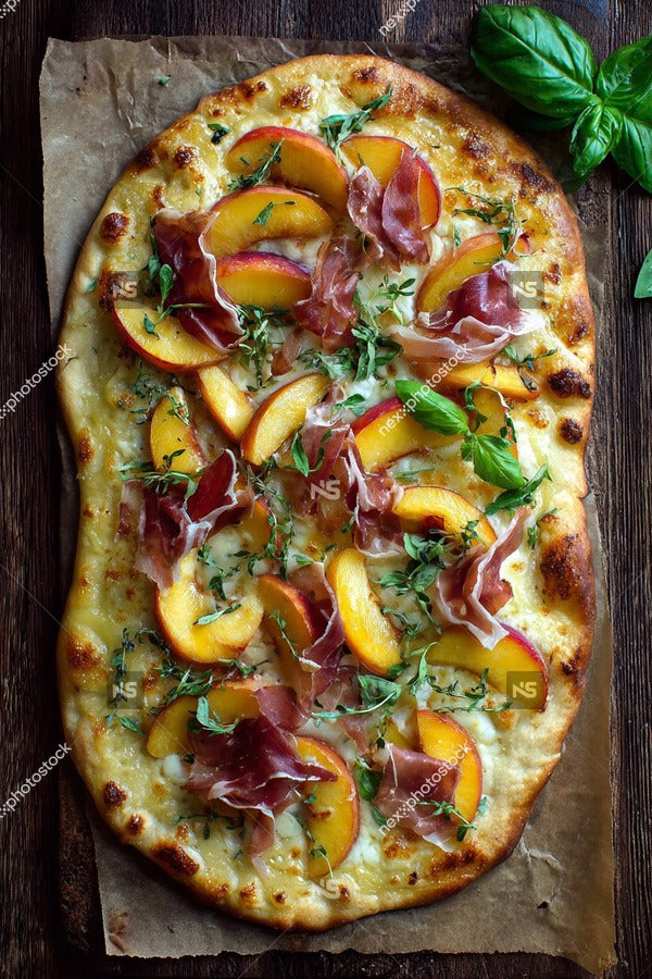 A Pizza Topped With Sliced Peaches Prosciutto And Basil Leaves On A Wooden Cutting Board — Stock Photo