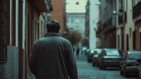 A Man Walking Down A Narrow Street In An Urban Setting With Buildings On Either Side And Cars Parked Along The Road — Stock Photo