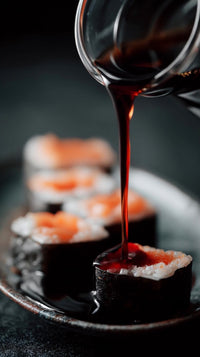 a plate of sushi rolls with salmon served with a bottle of soy sauce for dipping - Stock Video
