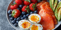 Breakfast Platter With Smoked Salmon Boiled Eggs Blueberries Red Strawberries And Seasoning On A Gray Plate — Stock Photo
