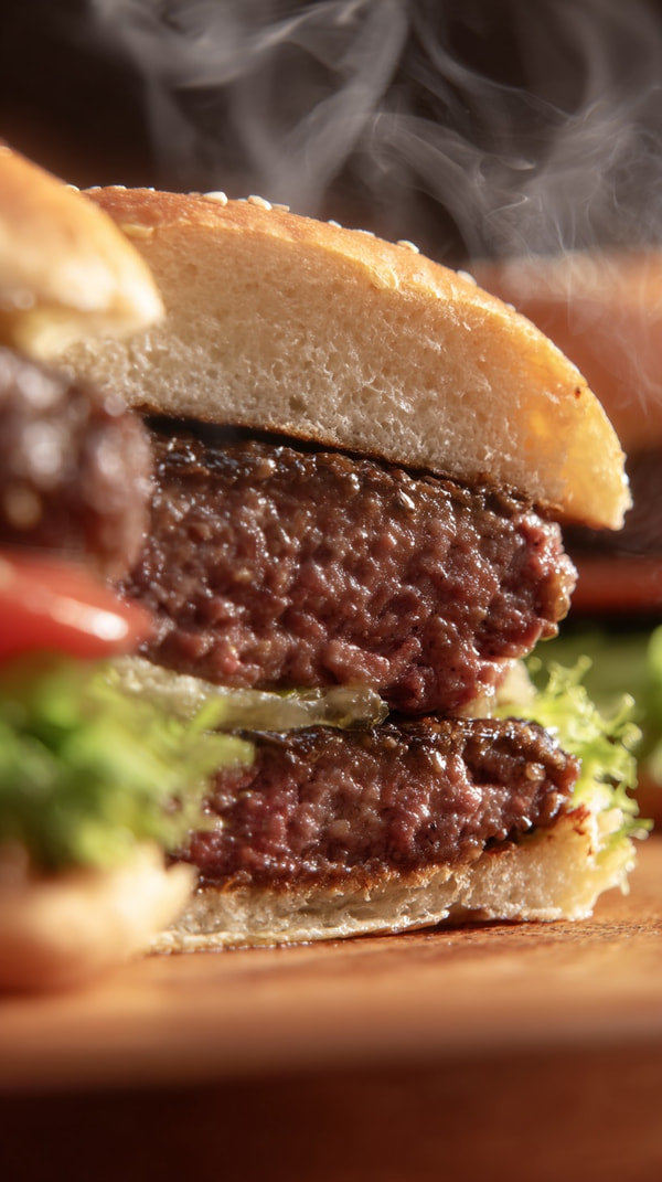 A Sesame Seed Bun With A Burger Patty Lettuce And Tomato On A Wooden Surface — Stock Photo