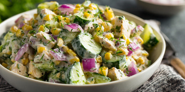 A Bowl Of Tasty Greek Salad With Visible Ingredients Such As Cucumbers Tomatoes And Chicken Shrimp Is Presented On A Table — Stock Photo