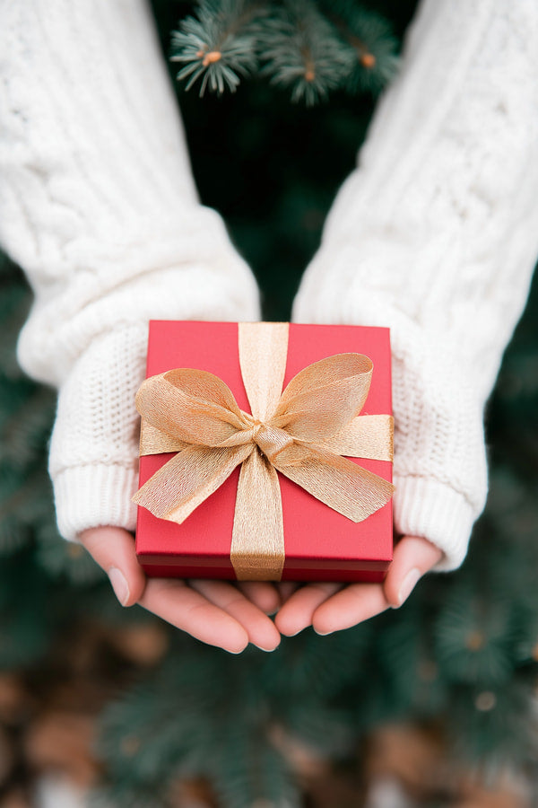 A Person Holding A Red Gift Box With A Gold Ribbon Set Against A Festive Background — Stock Photo