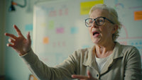 A 70 Year Old Woman Stands In An Office Setting Gesturing With Her Hands As She Speaks Passionately To Someone Out Of Frame — Stock Photo
