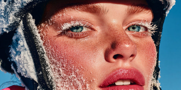 A Young Woman With Snowflakes On Her Face Wearing A Helmet And Goggles Poses For A Portrait Against A Blue Background — Stock Photo