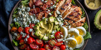 A Colorful Chicken Caesar Salad With Bacon Eggs And Tomatoes On A Black Plate — Stock Photo
