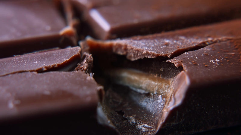 shows a close up view of a chocolate bar with its wrapper partially torn open - Stock Video