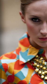 A Woman Wearing A Colorful Outfit With A Geometric Pattern Including A Jacket And A Necklace — Stock Photo
