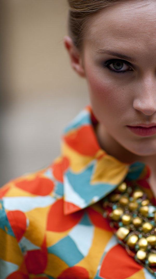 A Woman Wearing A Colorful Outfit With A Geometric Pattern Including A Jacket And A Necklace — Stock Photo