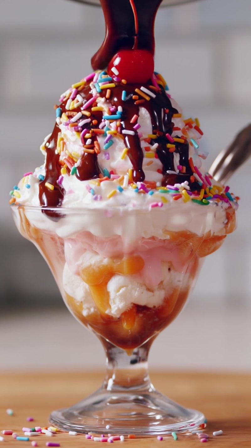 a delicious ice cream sundae with chocolate sauce and sprinkles served in a glass dish on a dining table - Stock Video