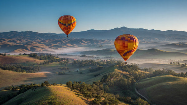Hot Air Balloons In Flight Over Rolling Hills And Valleys With Clear Blue Skies And A Few Scattered Clouds — Stock Photo