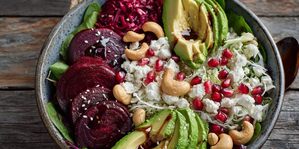 A Vibrant Salad Bowl Filled With A Variety Of Vegetables Including Pomegranate Seeds And Beets Is Presented On A Wooden Table — Stock Photo