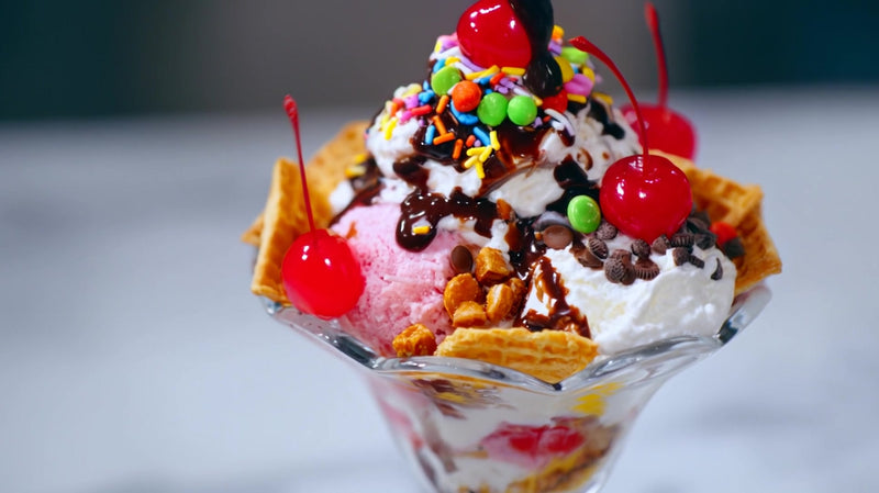 a scoop of ice cream topped with chocolate sauce sprinkles and whipped cream in a glass dish - Stock Video