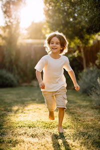 a young boy is running through a grassy area during sunset with sunlight casting shadows on the ground - Stock Video