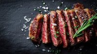 A Large Piece Of Steak Seasoned With Salt And Pepper Placed On A Black Surface — Stock Photo