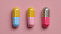 Five Capsules Of Vitamins Each With A Different Color Coating Arranged In A Row On A Pink Background — Stock Photo