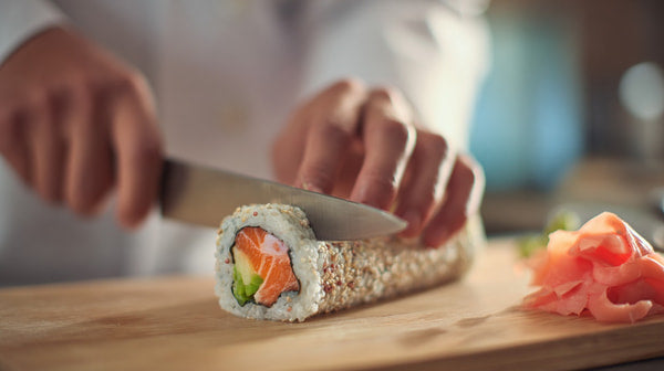A Chef Preparing A Sushi Roll With A Knife And Ingredients On A Cutting Board — Stock Photo