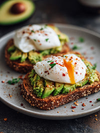 A Plate Of Avocado Toast Topped With Fried Eggs Garnished With Red Pepper Flakes And A Sprig Of Parsley — Stock Photo