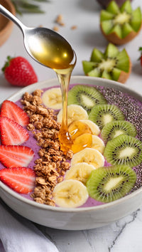 a bowl of banana smoothie topped with granola drizzled with honey and garnished with sliced bananas and strawberries - Stock Video
