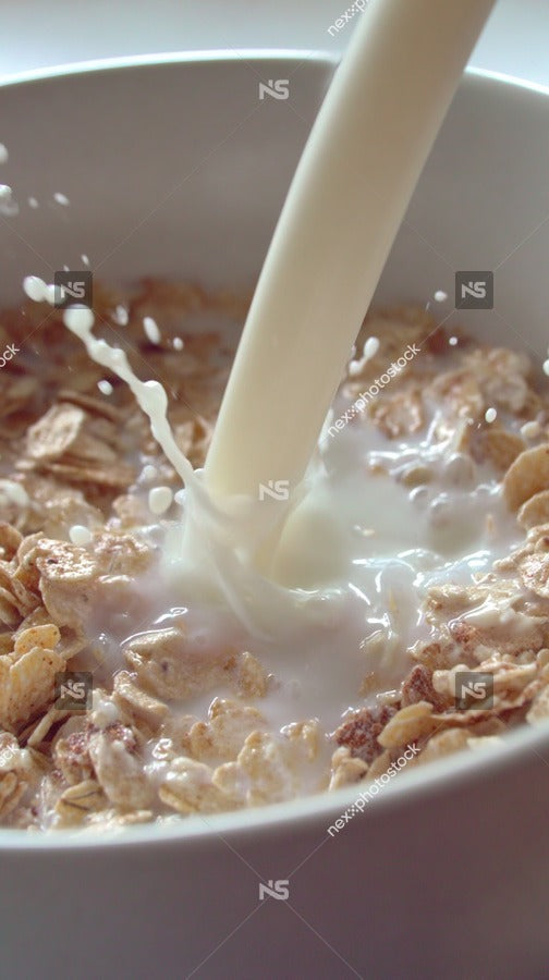 Milk Pouring From Container Into Cereal Bowl — Stock Photo