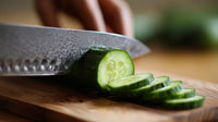 A Person Slicing A Cucumber On A Cutting Board With A Knife — Stock Photo