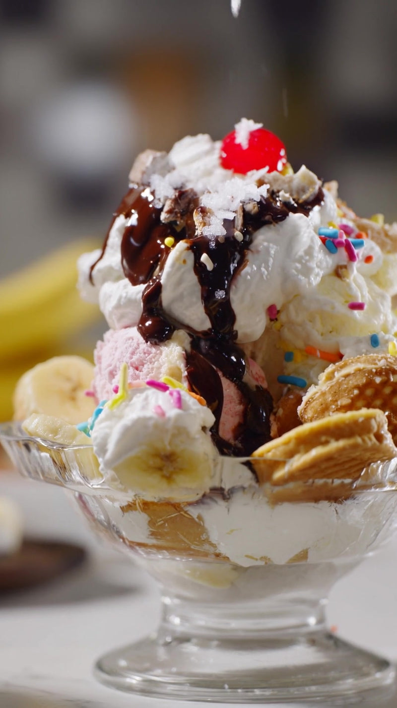 shows a large ice cream sundae in a glass bowl with whipped cream and chocolate syrup on top - Stock Video
