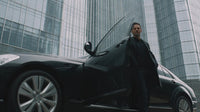 a composite of two separate photographs an urban setting and a man in a suit standing next to a black car - Stock Video